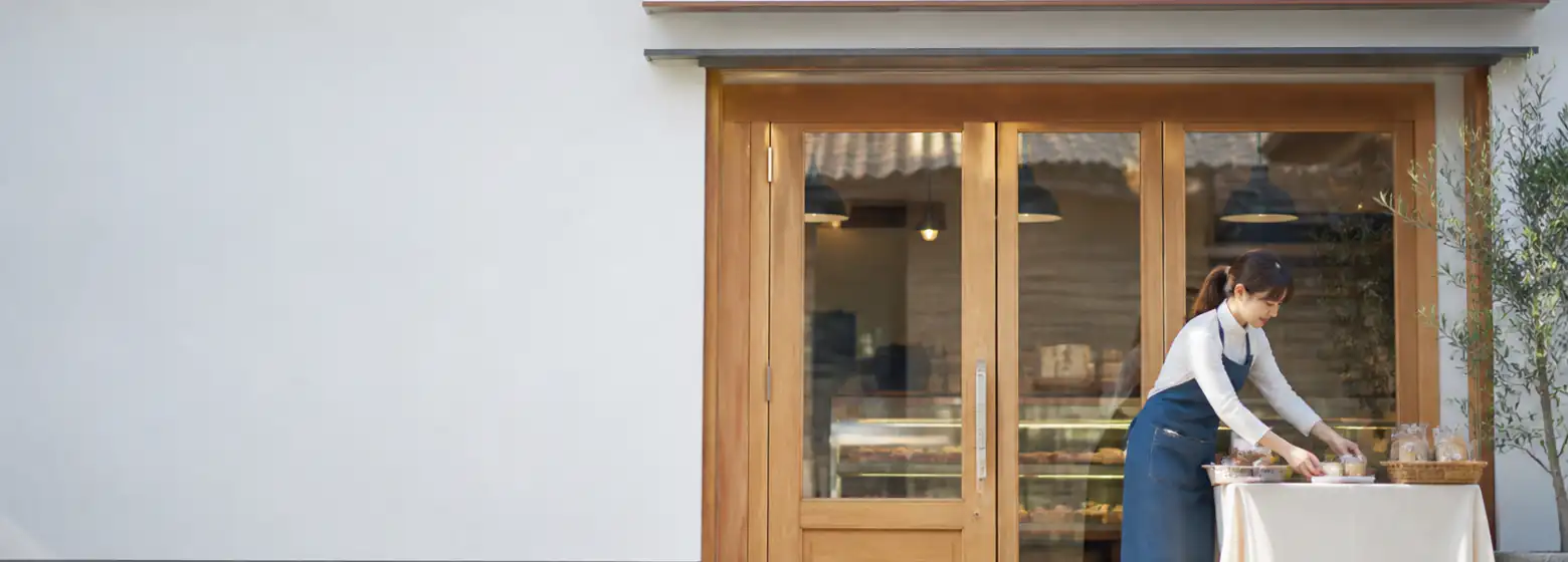 改装された小さな店舗の外観と、開店準備をする店主